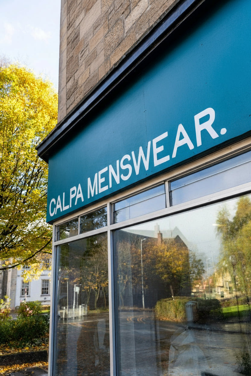 Storefront with 'CALPA MENSWEAR' sign on a building exterior