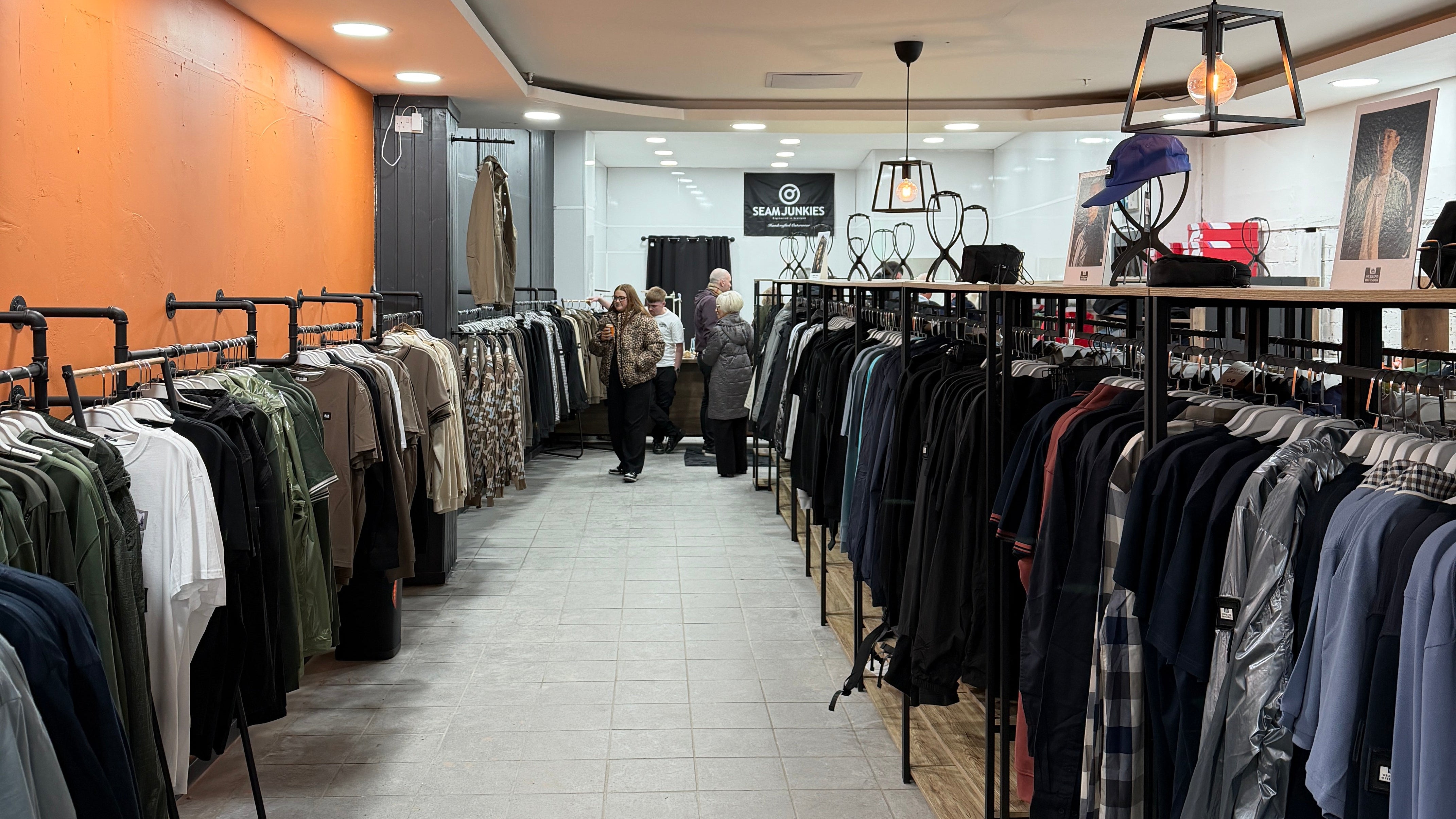 Clothing racks with shirts against a tiled wall in a store setting